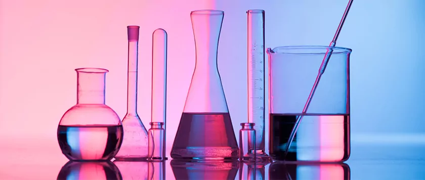 different lab glassware against a blue and pink tinted background