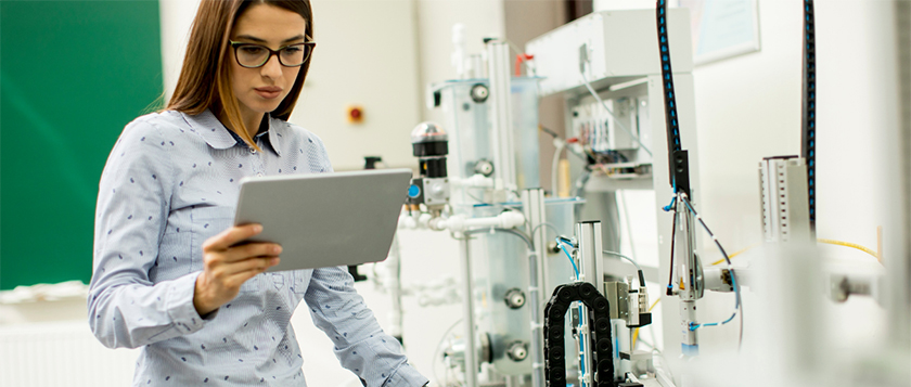 female student of robotics standing in a lab holding a digital tablet