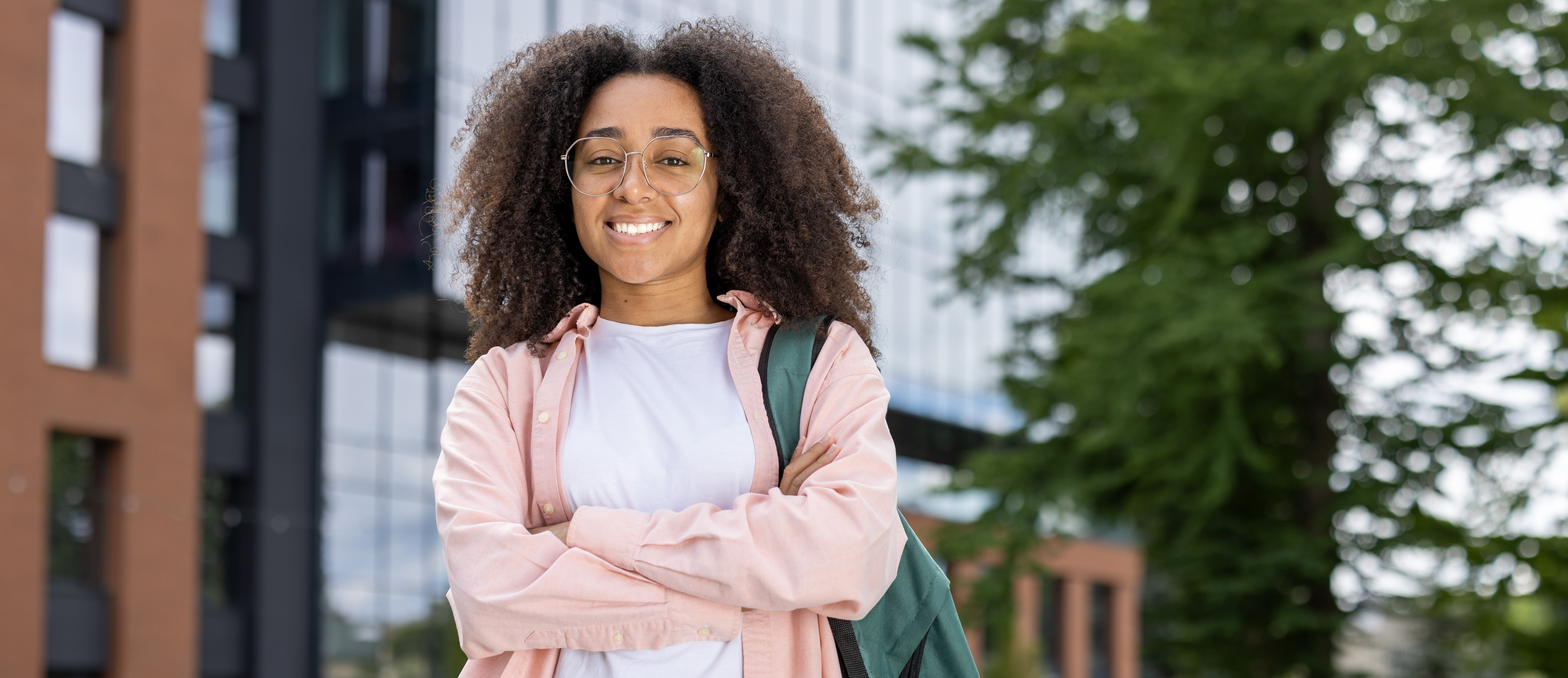 Teen female student posing confidently with backpack in front of a school
