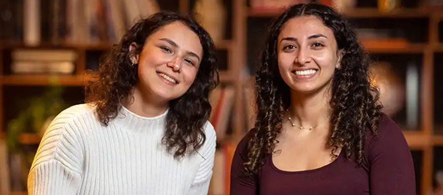 Two Pioneer alumni in front of bookshelves at the University of Pennsylvania.