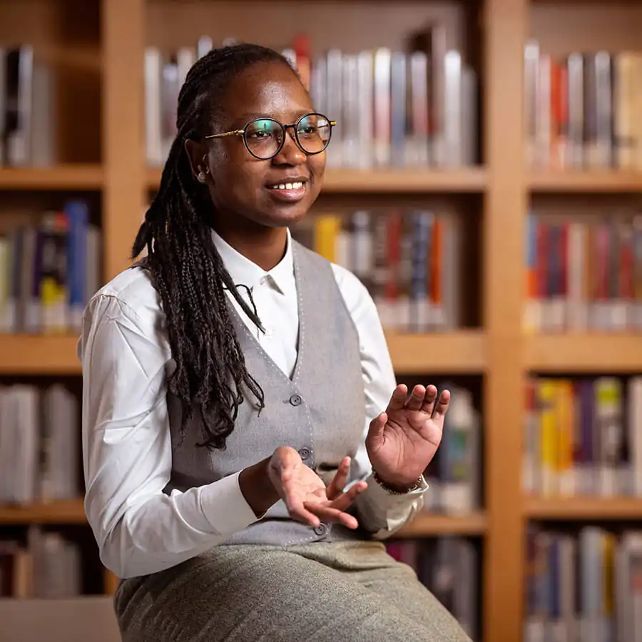Pioneer alumna gestures while speaking in a library at Princeton.