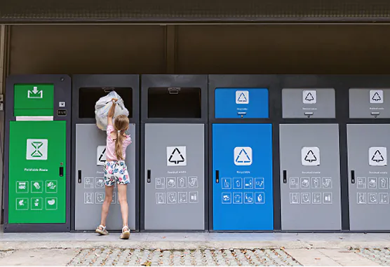 Young girl recycling into separated containers.